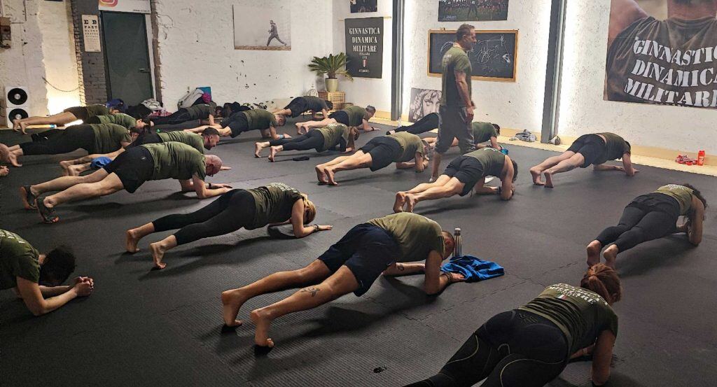 Un gruppo tiene la posizione di plank sul pavimento di una palestra